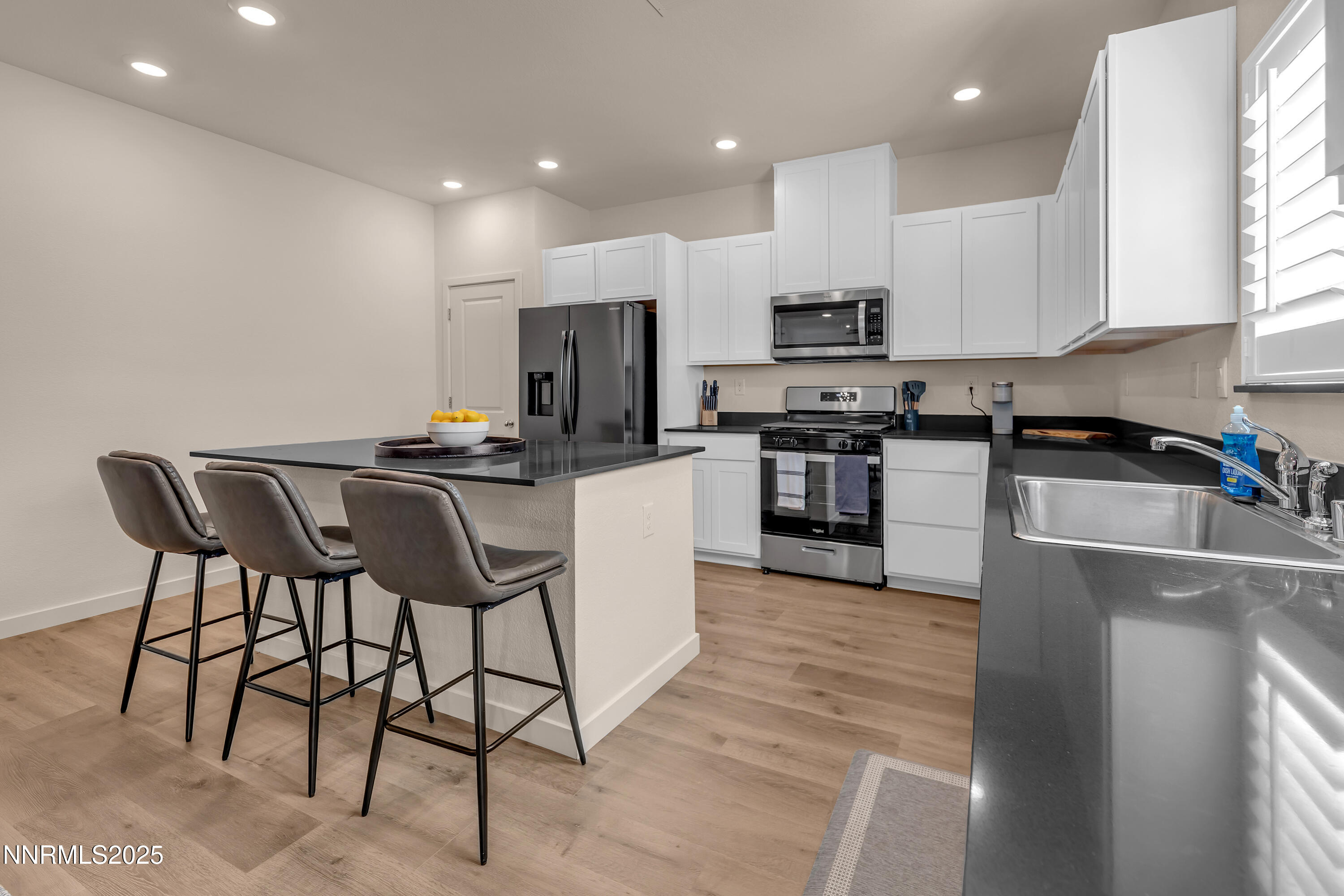 7754 Wandering Way Reno, NV 89506 - Photo 8 of 37 a kitchen with stainless steel appliances kitchen island granite countertop a stove a sink a microwave a dining table and chairs