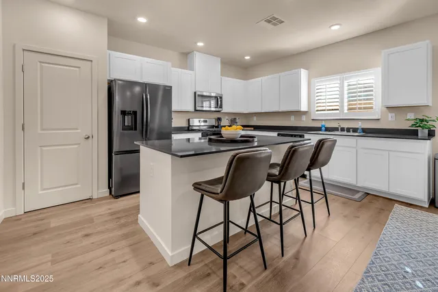 a kitchen with stainless steel appliances granite countertop a table chairs refrigerator microwave and cabinets