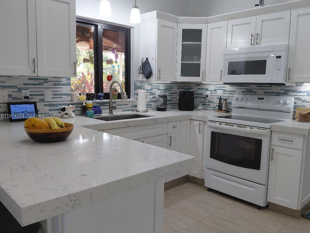15630 Southwest 146th Avenue Miami, FL 33177 - Photo 6 of 23 a kitchen with stainless steel appliances a stove sink microwave and cabinets