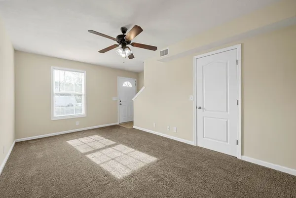 an empty room with windows and fan