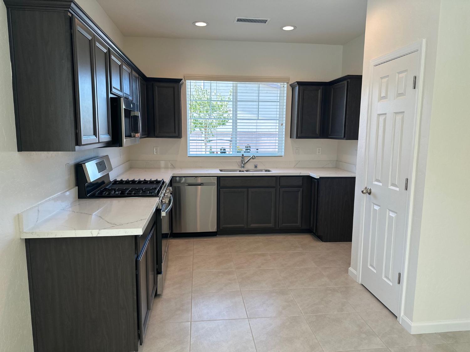 573 Green Lane Lemoore, CA 93245 - Photo 2 of 7 a kitchen with stainless steel appliances granite countertop a sink stove and refrigerator