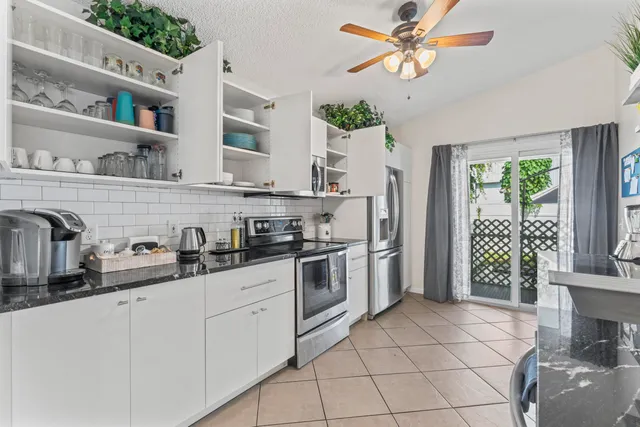 a kitchen with stainless steel appliances a sink a stove a refrigerator cabinets and a window