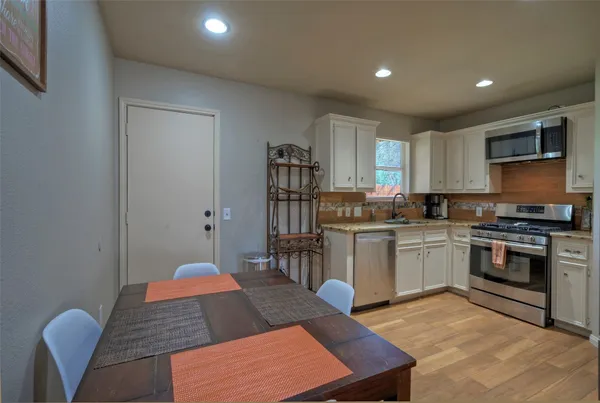 a open kitchen with stainless steel appliances granite countertop a stove a sink a dining table and chairs