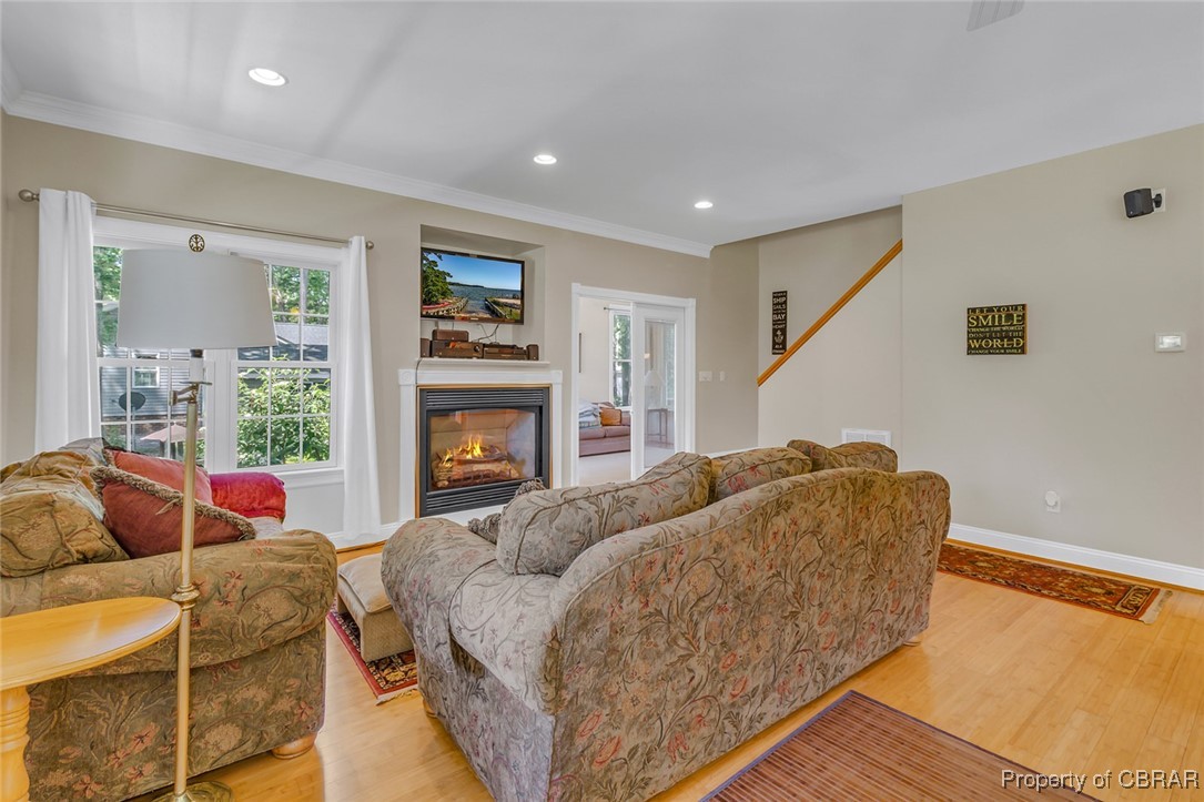 189 Virginia Road Reedville, VA 22539 - Photo 14 of 46 Living room featuring light wood-style flooring, crown molding, a glass covered fireplace, recessed lighting, and baseboards