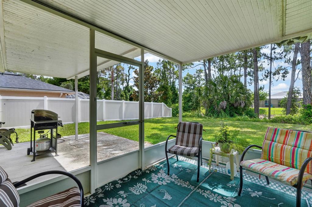80 Roxboro Drive Palm Coast, FL 32164 - Photo 22 of 39 a view of a patio with table and chairs potted plants and a palm tree