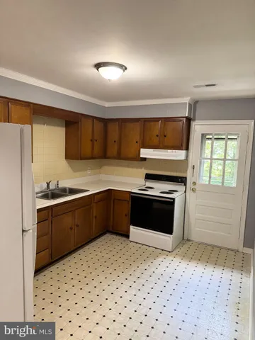 a kitchen with granite countertop a stove a sink and a refrigerator