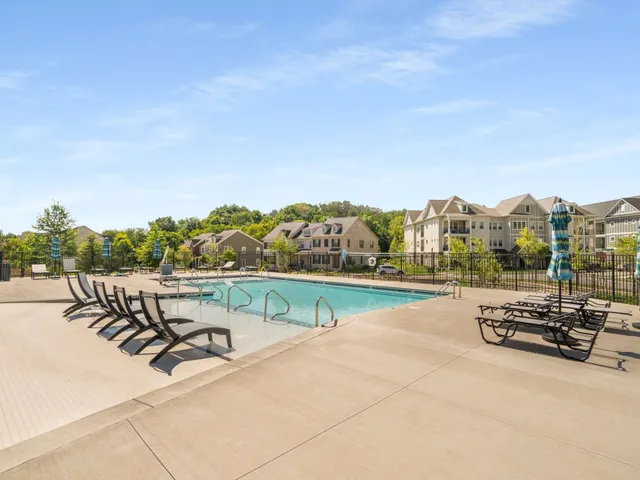 a view of swimming pool with seating space and trees in the background