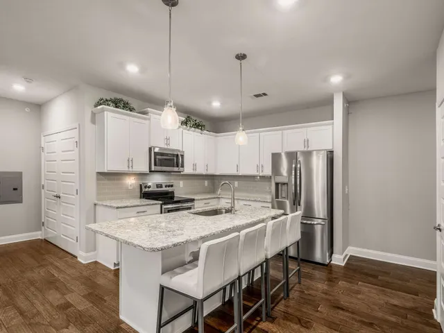 a kitchen with stainless steel appliances granite countertop a refrigerator a sink dishwasher a stove and a refrigerator with wooden floor