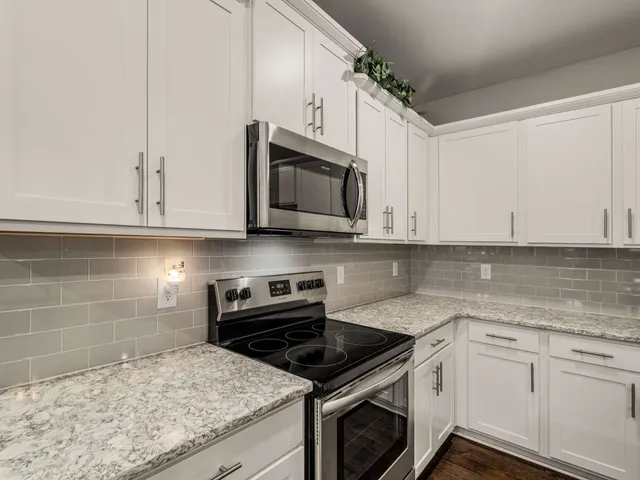 a kitchen with stainless steel appliances granite countertop white cabinets granite counter tops and a hard wood floors