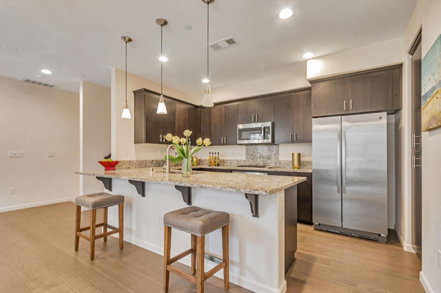 1890 Trento Loop Milpitas, CA 95035 - Photo 5 of 39 a kitchen with kitchen island a dining table chairs refrigerator and microwave