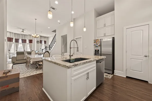 a kitchen with granite countertop a sink stainless steel appliances and living room view