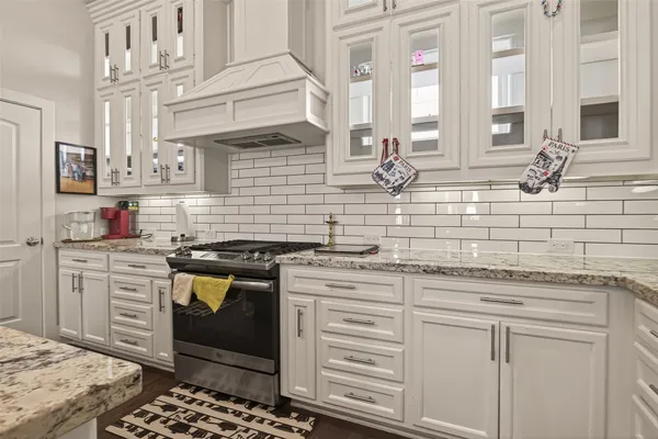 a kitchen with stainless steel appliances granite countertop a sink stove and white cabinets with wooden floor