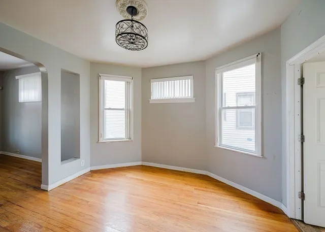 an empty room with wooden floor fan and windows