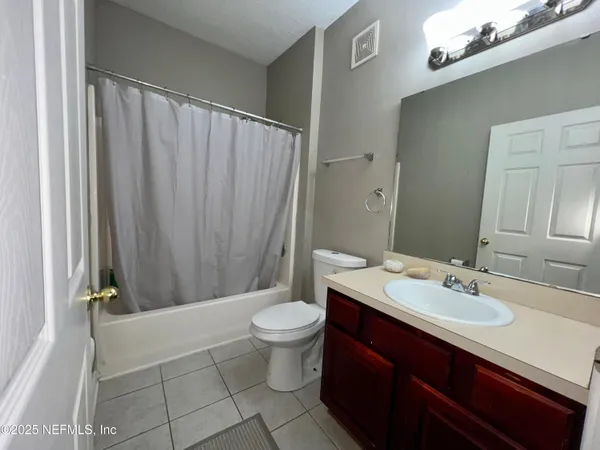 a bathroom with a sink a toilet a mirror and shower curtain