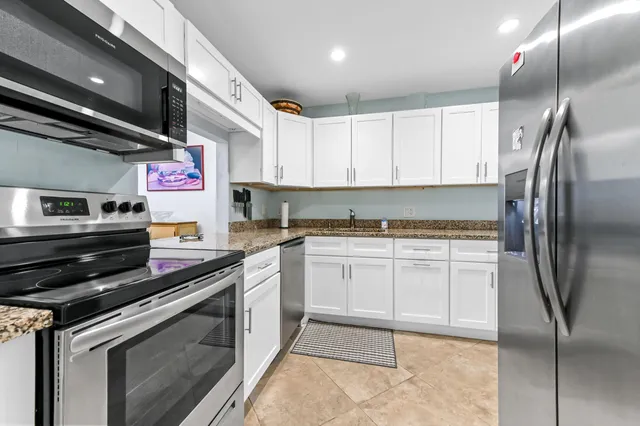 a kitchen with stainless steel appliances granite countertop a stove a refrigerator and a sink
