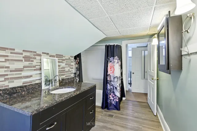 a bathroom with a granite countertop shower a sink and a mirror