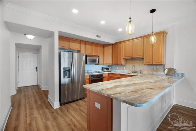 a kitchen with granite countertop a refrigerator a sink and wooden floor