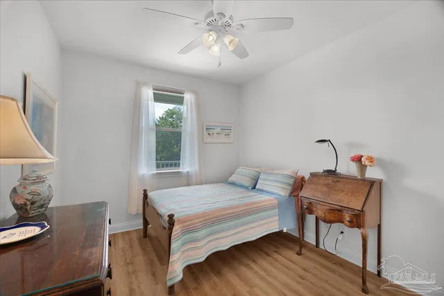 a bedroom with a bed and a dresser with wooden floor