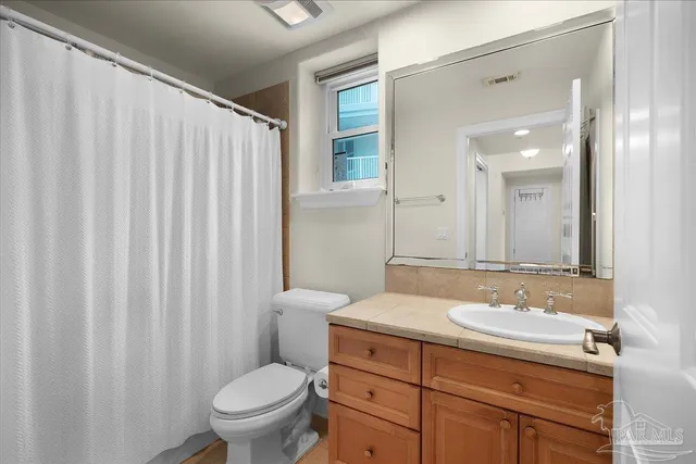 a bathroom with a granite countertop sink a toilet and a mirror