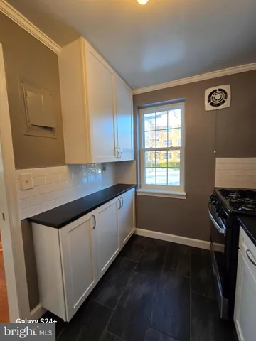 a kitchen with granite countertop white cabinets and black appliances