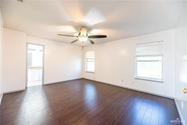 an empty room with wooden floor fan and windows
