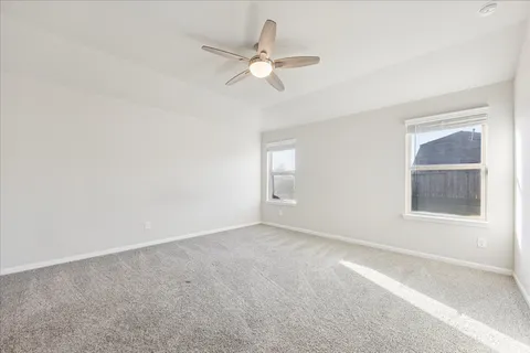 an empty room with windows and fan
