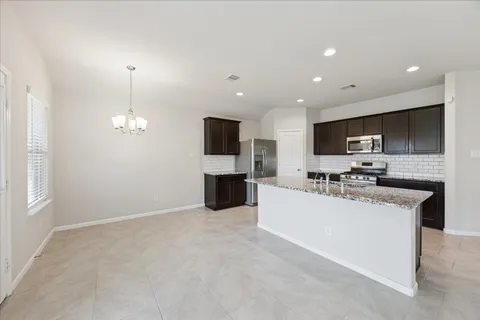 a large kitchen with a large counter top stainless steel appliances and cabinets