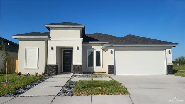 a view of a house with small yard plants and a garage
