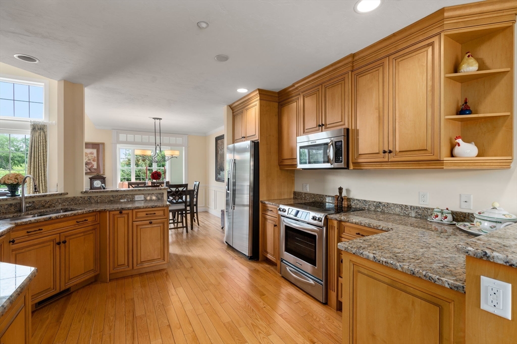7 English Cmns, Unit 7 Topsfield, MA 01983 - Photo 7 of 36 a kitchen with stainless steel appliances granite countertop wooden cabinets a refrigerator a sink a stove a microwave and wooden floors