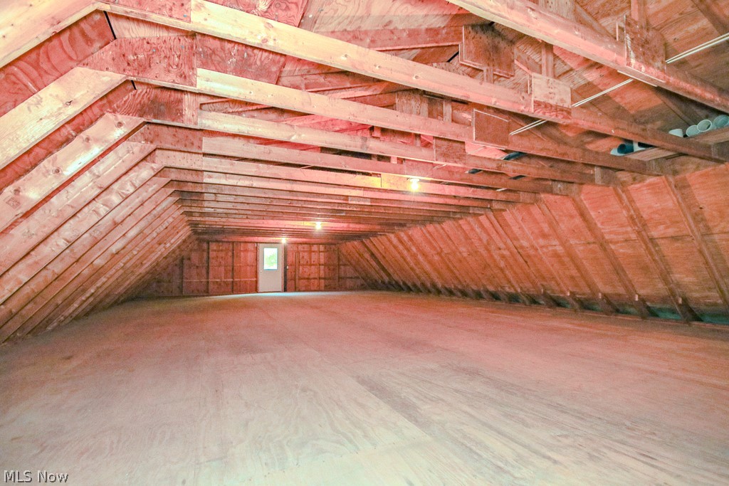 6475 Taylor Road Painesville, OH 44077 - Photo 21 of 23 Spacious 2 of 2 outbuilding attic space featuring exposed wood framing, wood-finish flooring, and a white paneled door