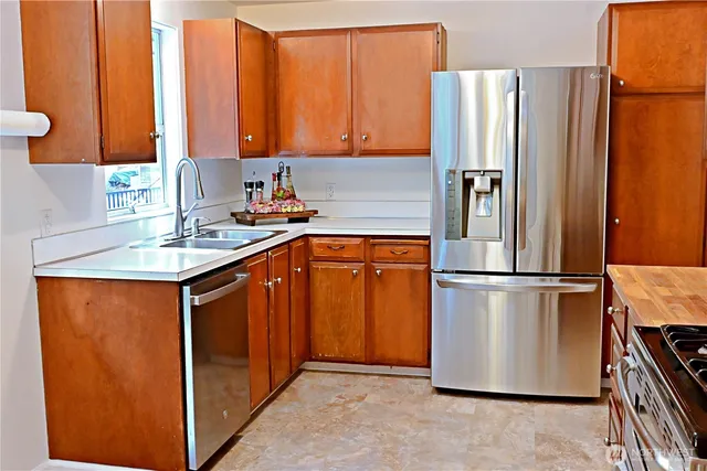 a kitchen with stainless steel appliances granite countertop a refrigerator a sink and a stove