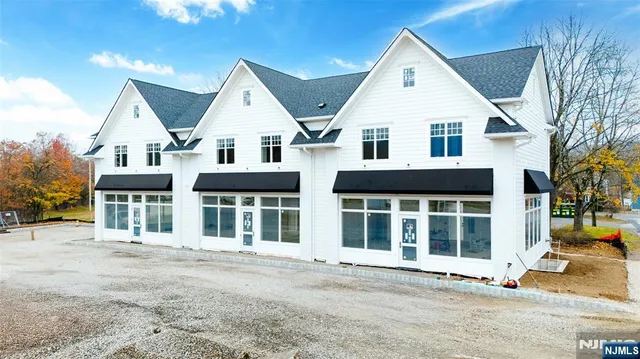 a view of a white house with large windows and a small yard