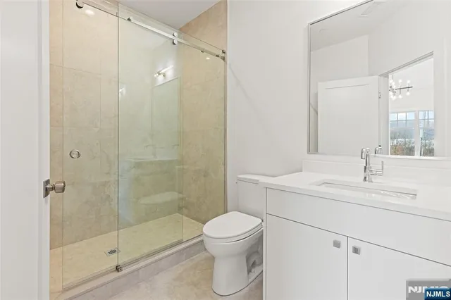 a bathroom with a shower sink vanity mirror and toilet