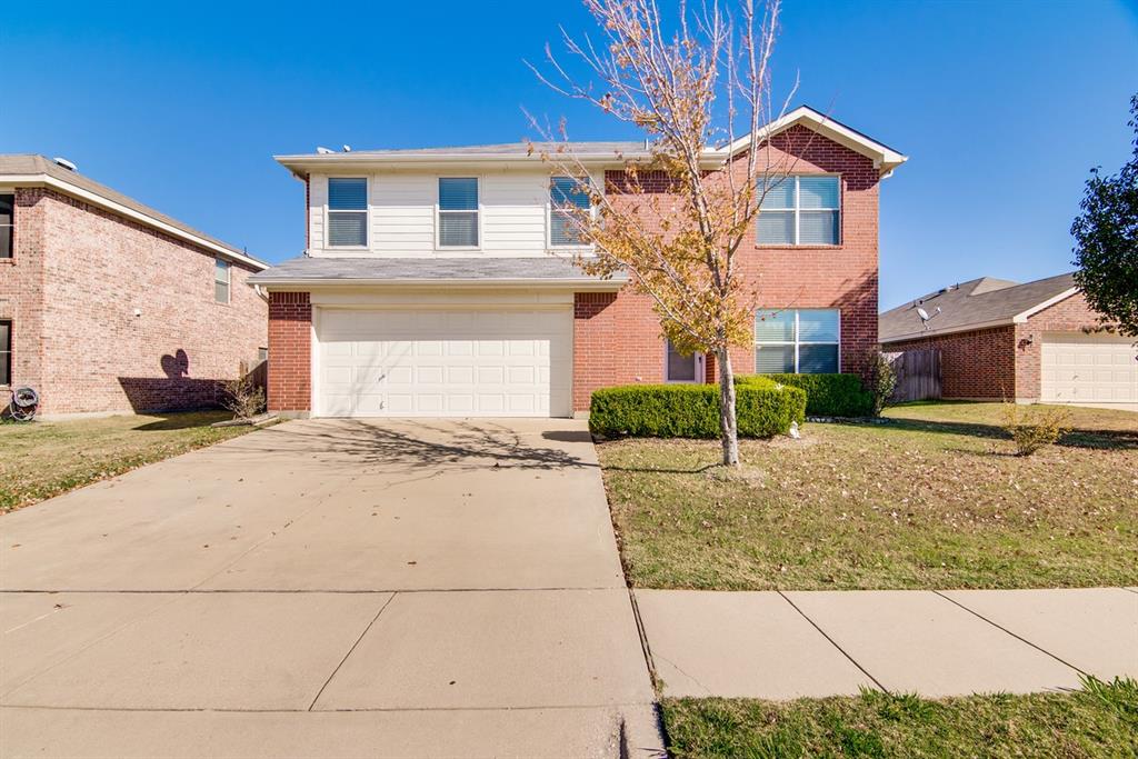 Traditional-style home with driveway, brick siding, a front yard, and a garage