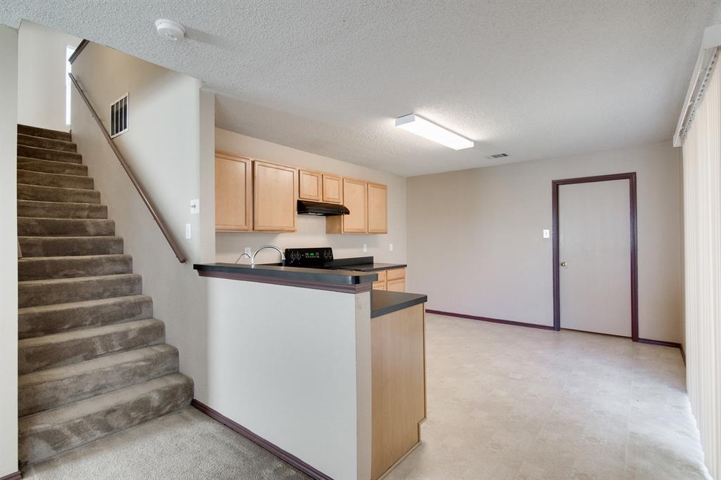 8211 Leaning Oak Court Arlington, TX 76002 - Photo 11 of 26 Kitchen featuring light brown cabinetry, dark countertops, a textured ceiling, black / electric stove, and under cabinet range hood