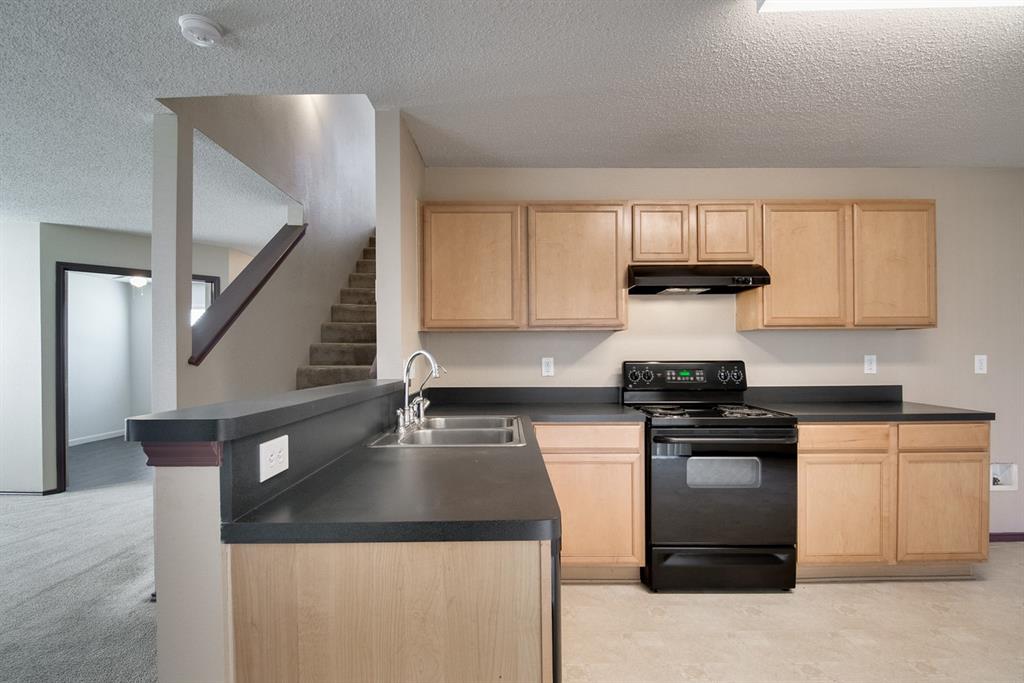 8211 Leaning Oak Court Arlington, TX 76002 - Photo 12 of 26 Kitchen with light brown cabinetry, a textured ceiling, black electric range, dark countertops, and under cabinet range hood