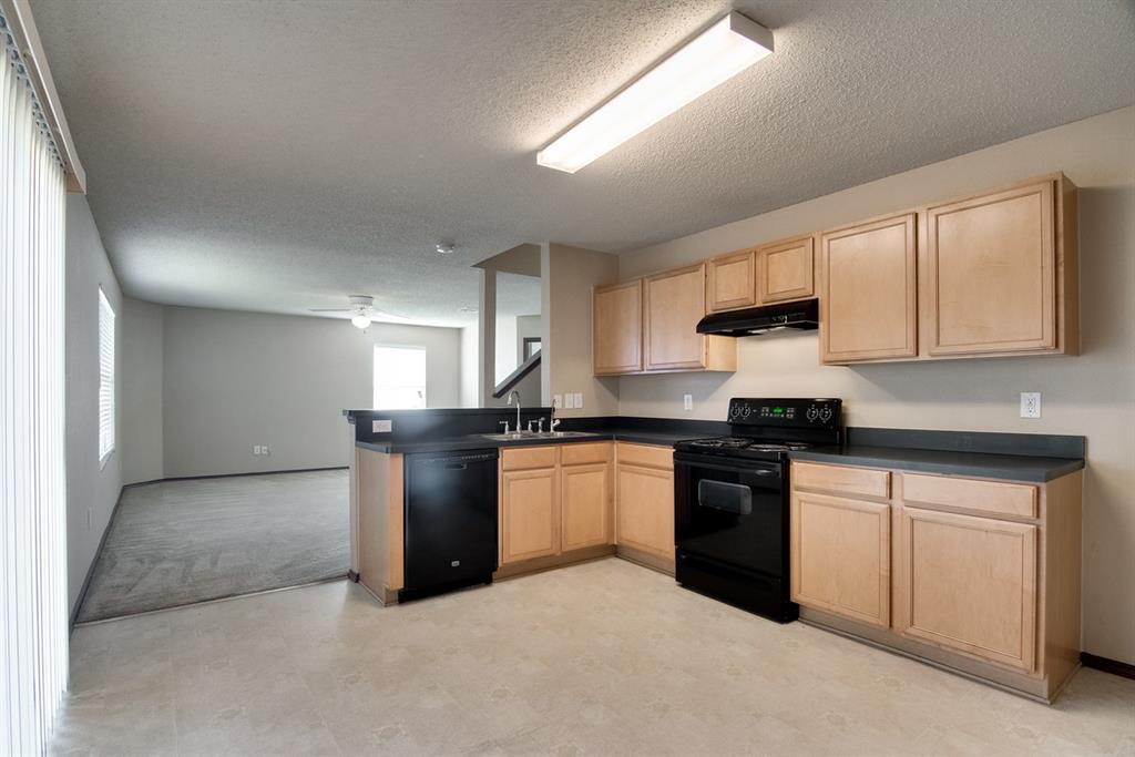 8211 Leaning Oak Court Arlington, TX 76002 - Photo 26 of 26 Kitchen featuring light brown cabinetry, black appliances, dark countertops, open floor plan, and a textured ceiling