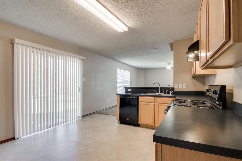 8211 Leaning Oak Court Arlington, TX 76002 - Photo 13 of 26 Kitchen with dark countertops, stainless steel electric range, a peninsula, light brown cabinets, and a textured ceiling