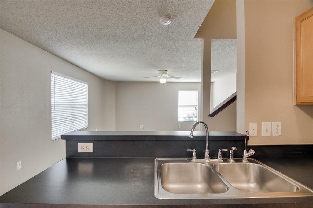 8211 Leaning Oak Court Arlington, TX 76002 - Photo 14 of 26 Kitchen with dark countertops, a textured ceiling, and a ceiling fan