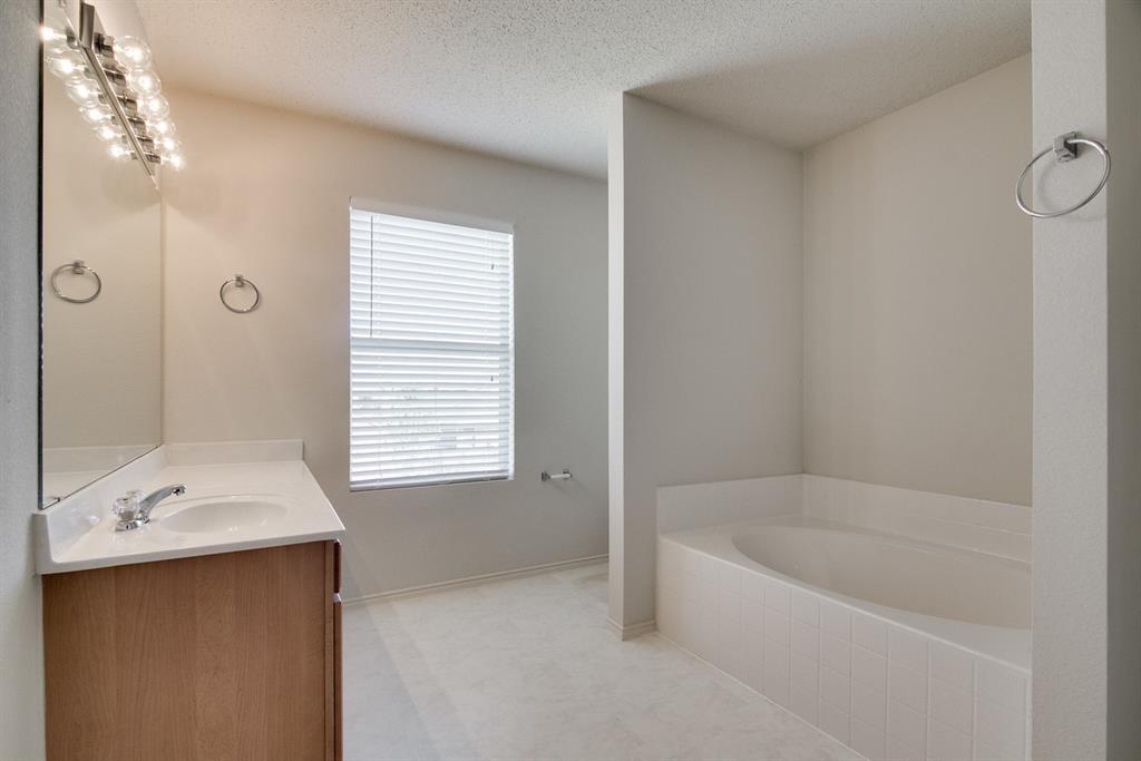 8211 Leaning Oak Court Arlington, TX 76002 - Photo 19 of 26 Full bathroom featuring vanity, a bath, and a textured ceiling