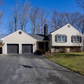 a front view of a house with a garden and trees