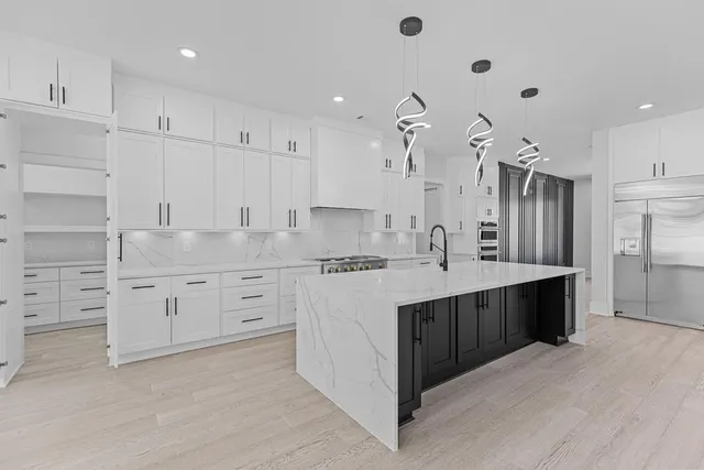a large white kitchen with lots of counter space wooden floor and appliances