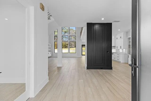 a view of an empty room with wooden floor and a bathroom