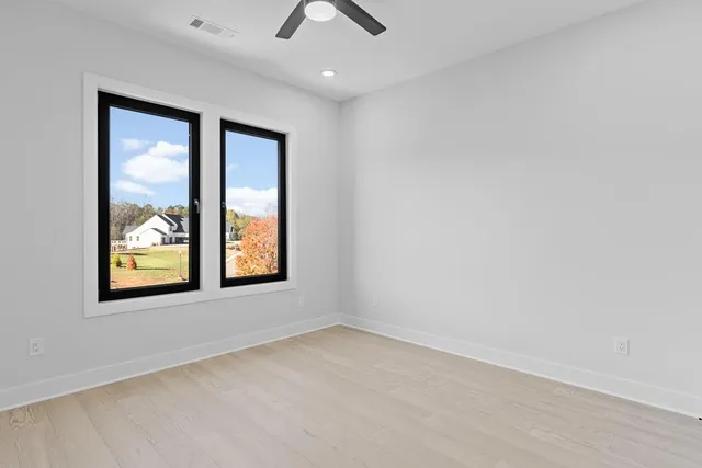 an empty room with a window and ceiling fan