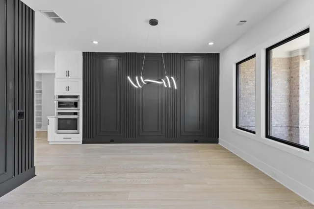 a view of an empty room with wooden floor and windows