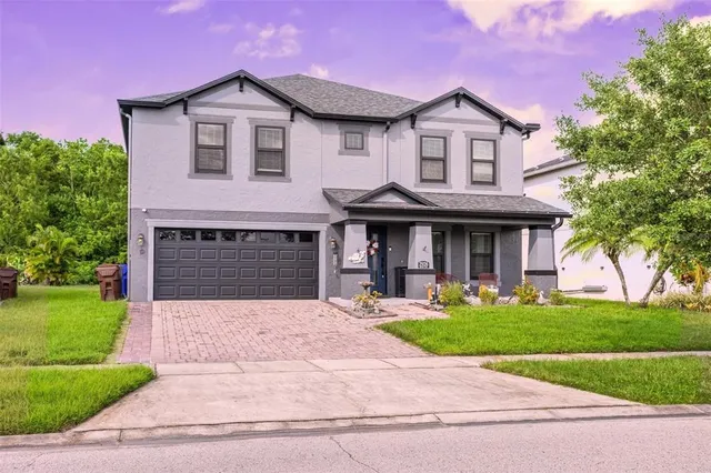 a front view of a house with garden and trees