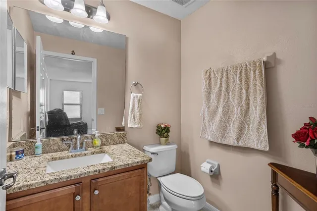 a bathroom with a granite countertop sink vanity mirror and toilet