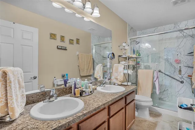 a bathroom with a granite countertop sink a toilet a mirror and shower