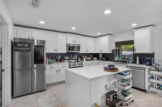 a kitchen with a sink a refrigerator and white cabinets