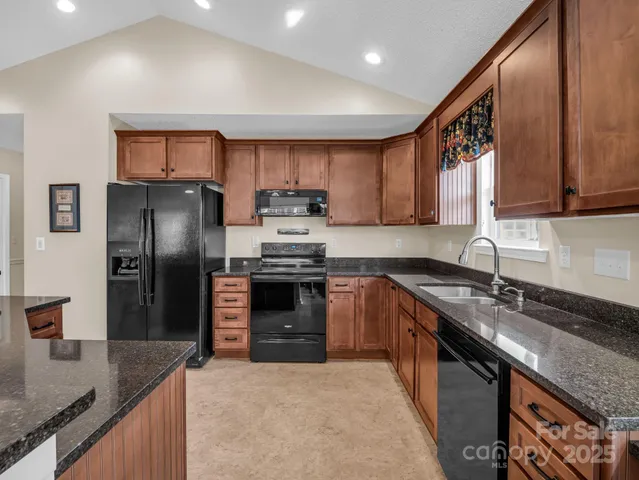 a kitchen with stainless steel appliances granite countertop a sink stove refrigerator and cabinets